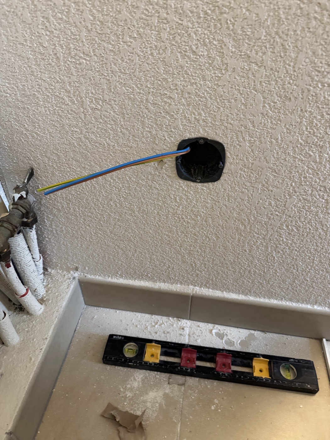 Boîte d'encastrement posée au niveau à bulle, câbles en attente de raccordement